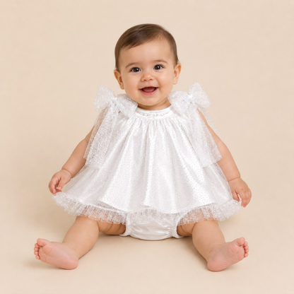 Bebe nina usando conjunto gala blanco tul brillante con lazos sentada sonriendo