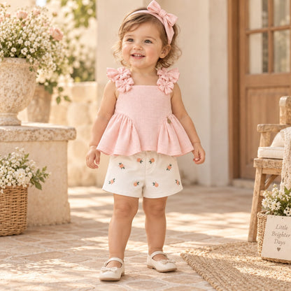 Niña de pie con conjunto rosa y short blanco bordado floral en exterior