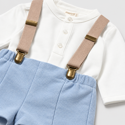 Vista posterior del conjunto de pantalón corto azul claro con tirantes y camisa blanca para bebé