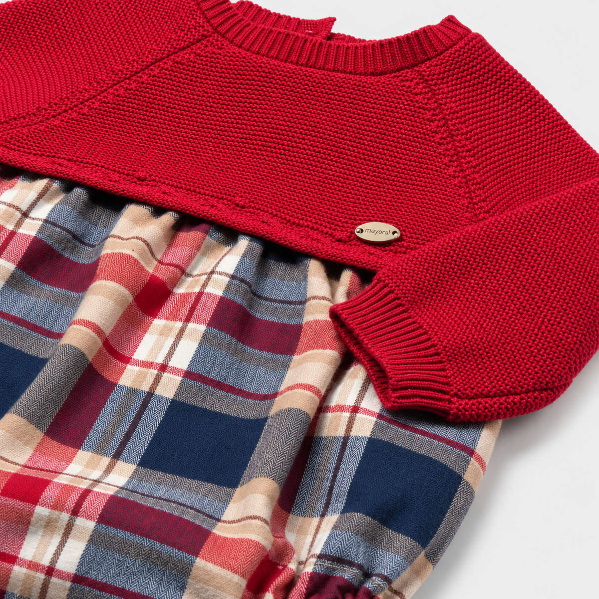 Detalle de jersey rojo tejido y pelele de cuadros del conjunto Mayoral para recién nacido