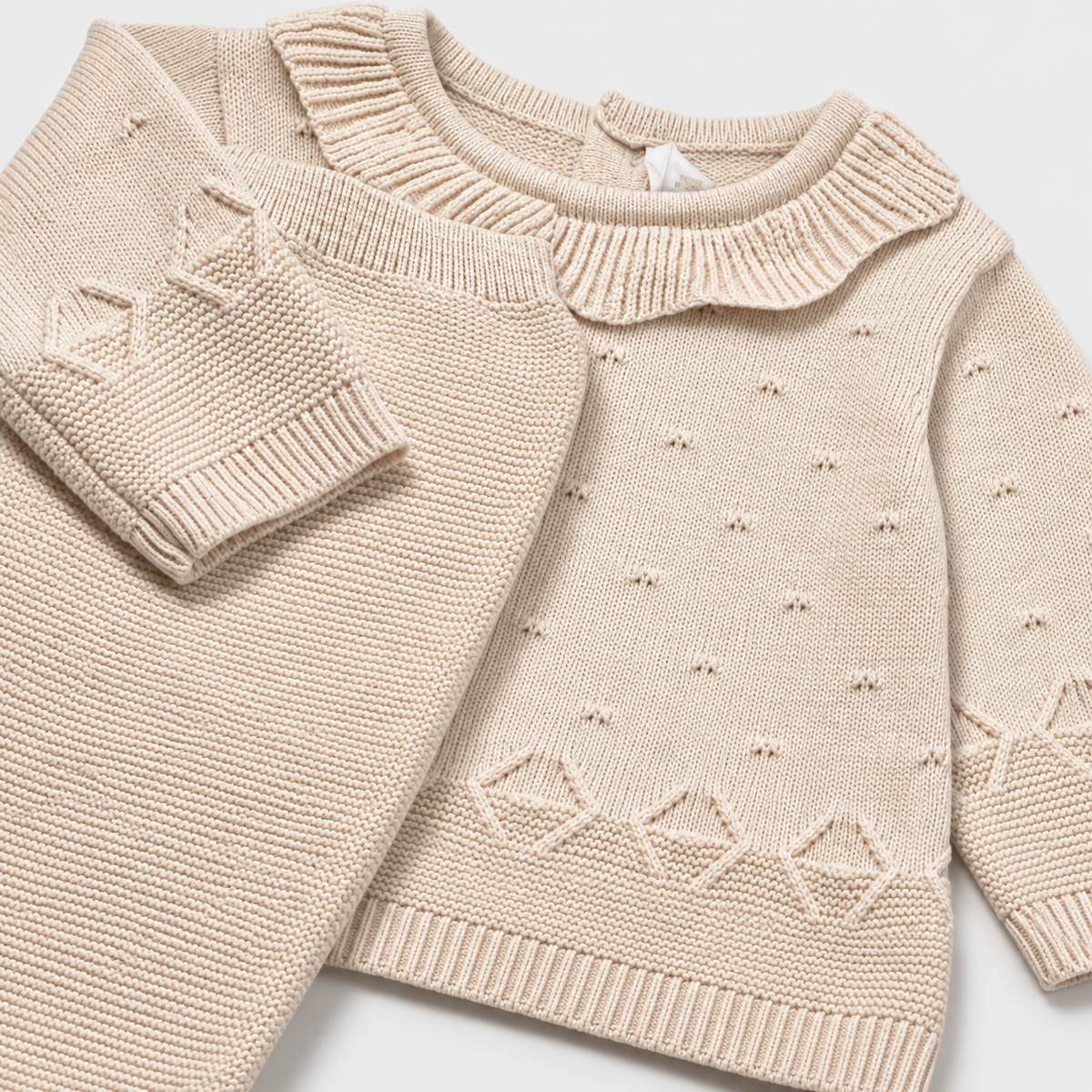 Detalle de jersey tricot beige con cuello de volantes y pantalón tejido para recién nacida