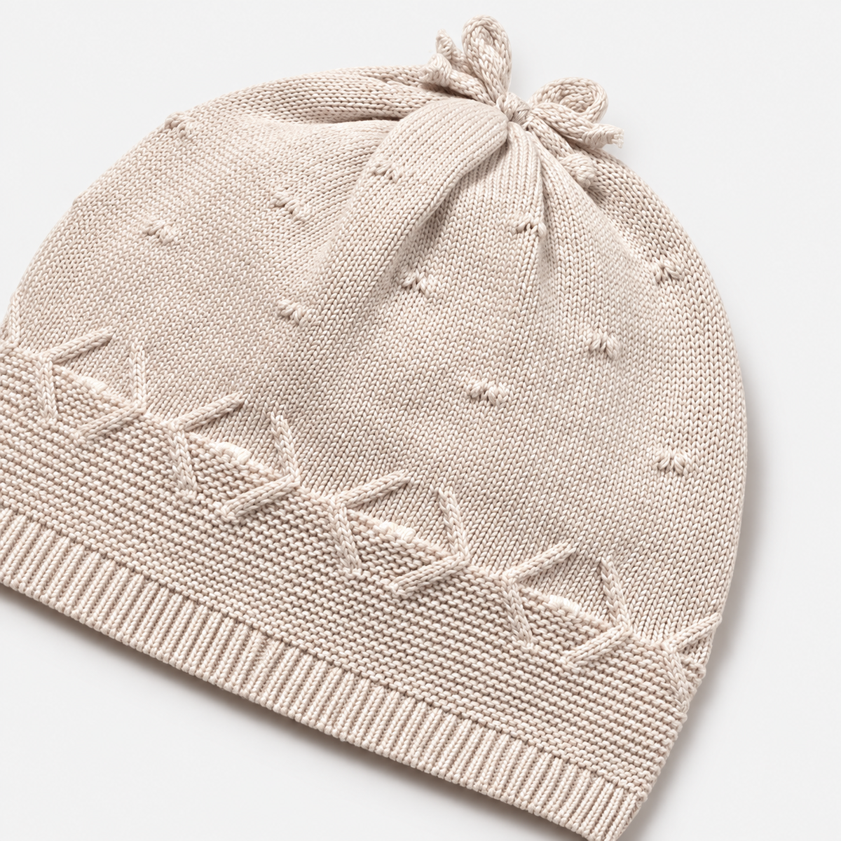 Gorro tricot beige con lazo y cenefa decorativa para recién nacida
