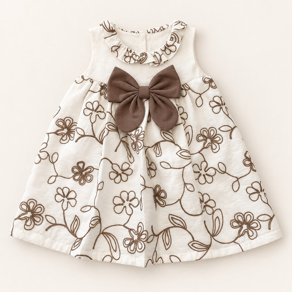 Bebé usando vestido marfil con flores café, cuello con volante y moño