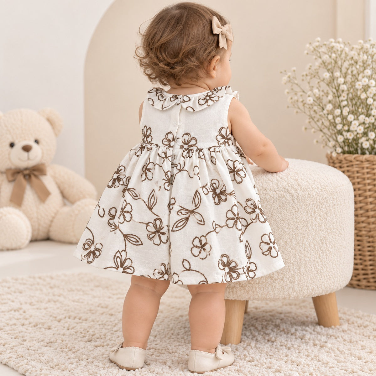 Bebé usando vestido marfil floral con moño café visto desde atrás