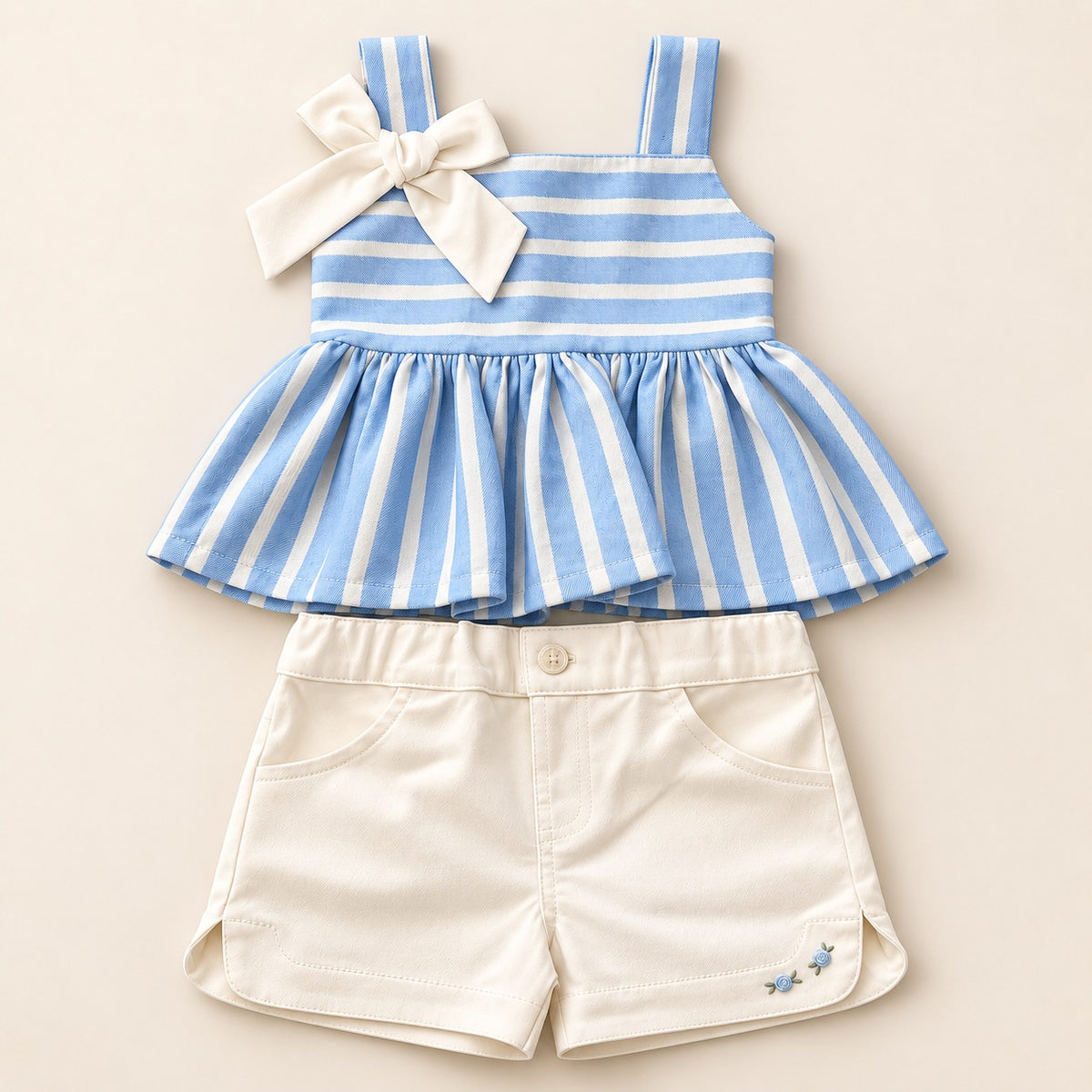 Detalle de conjunto infantil con blusa azul cielo de rayas, moño y short blanco
