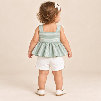 Niña usando conjunto verde salvia con blusa de tirantes, moño blanco y short