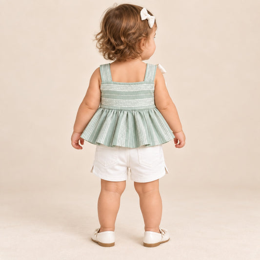 Niña usando conjunto verde salvia con blusa de tirantes, moño blanco y short