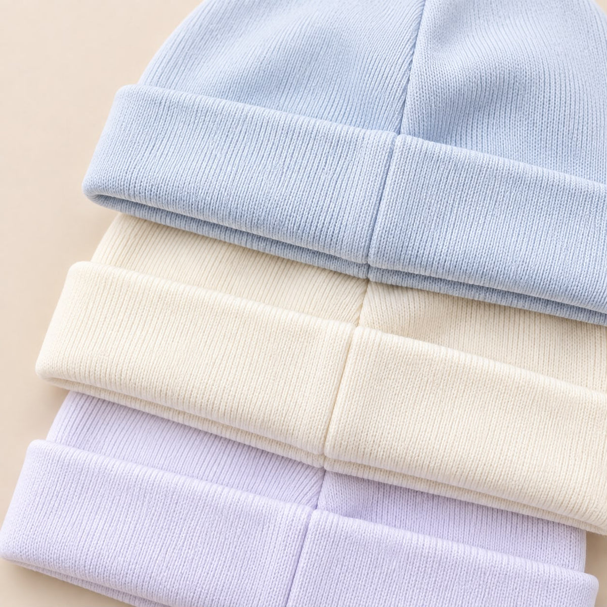 Empaque del set Bebé Feliz con tres gorros para bebé en rosado, blanco y azul claro