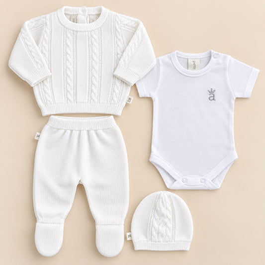 Cuatro piezas del conjunto tejido blanco para bebé extendidas: suéter, pantalón, body y gorro