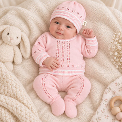 Detalle de suéter tejido rosado para bebé con diseño calado y puños con contraste blanco