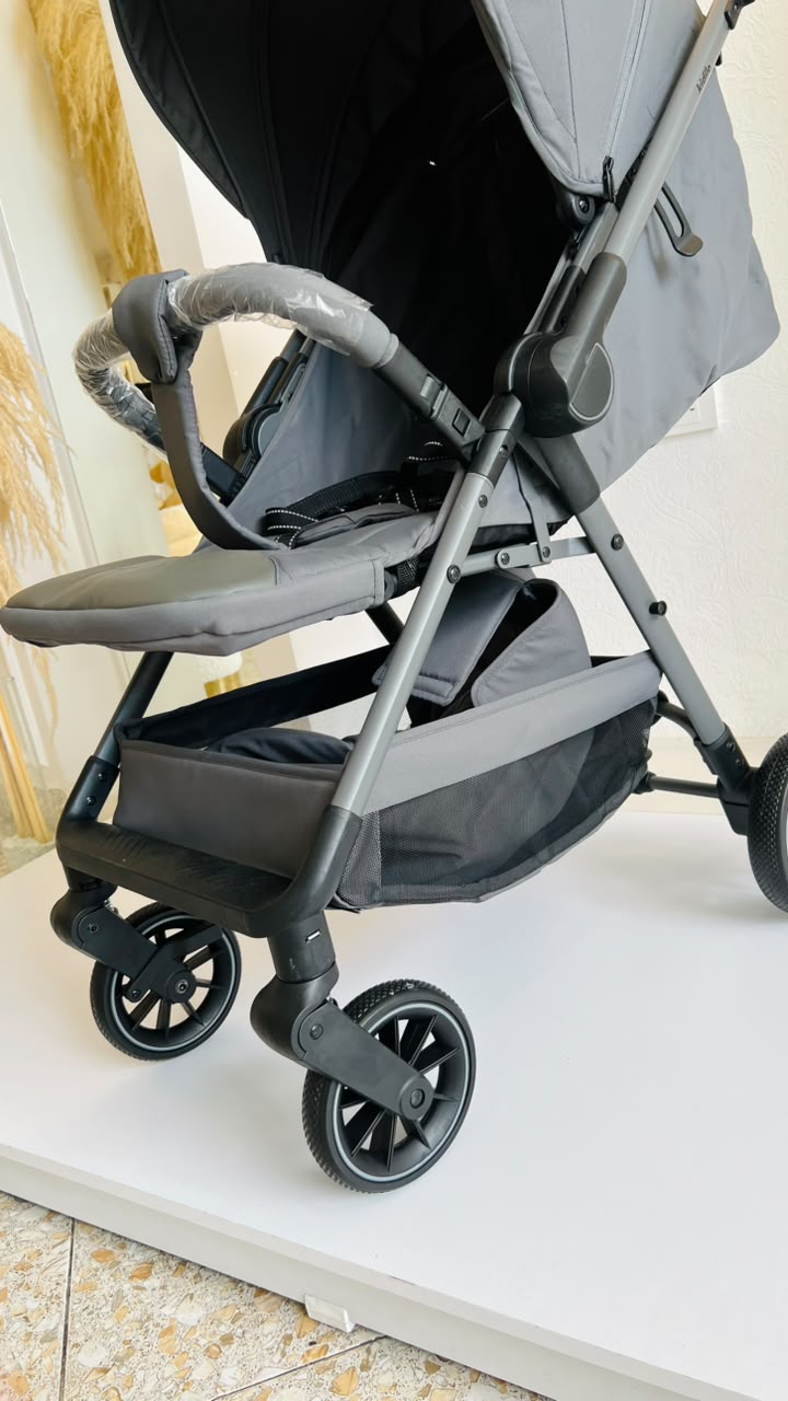 Coche para bebé gris con capota extendida, barra frontal y reposapiés