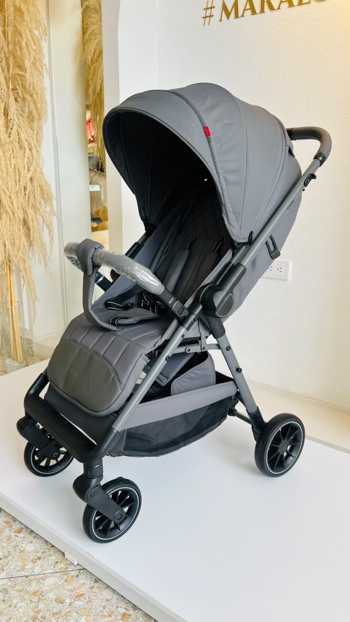 Vista frontal de coche gris para bebé con manillar, capota y asiento acolchado