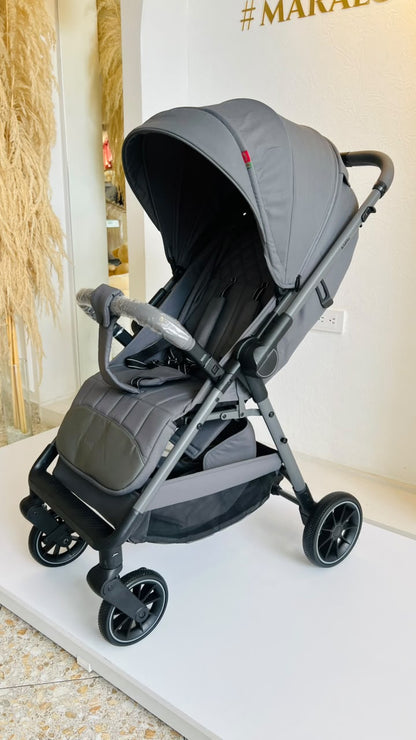 Vista frontal de coche gris para bebé con manillar, capota y asiento acolchado