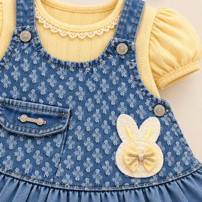 Vista posterior del vestido jardinera denim con ruedo fruncido, blusa amarilla y moños para el cabello