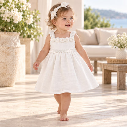 Niña sentada con vestido blanco marfil de rosas y diadema