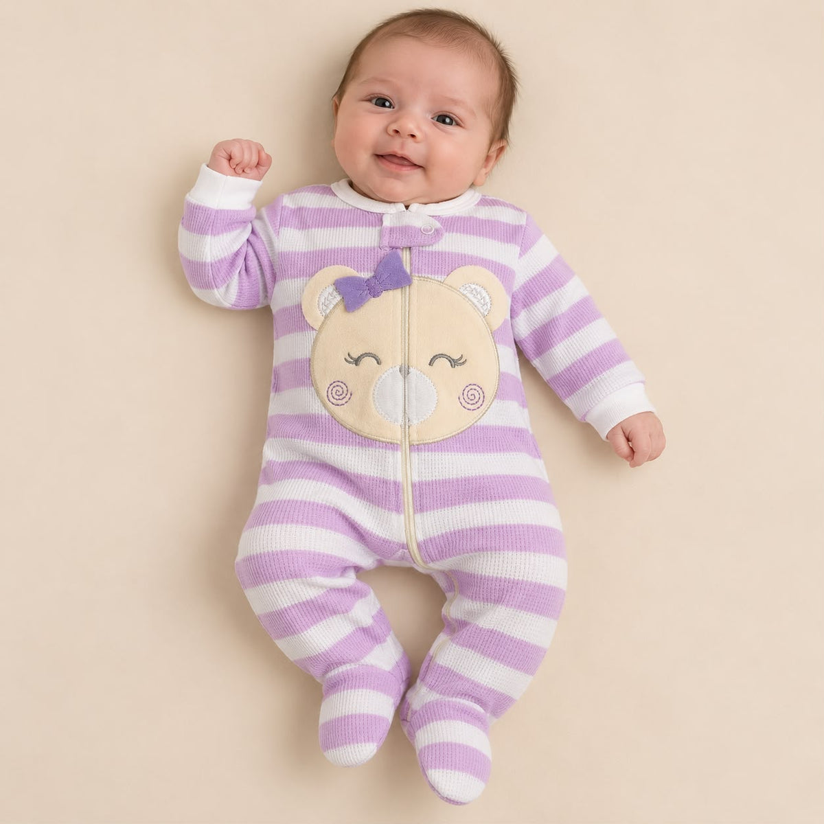 Bebé usando enterizo de rayas lila y blanco con aplique de osito