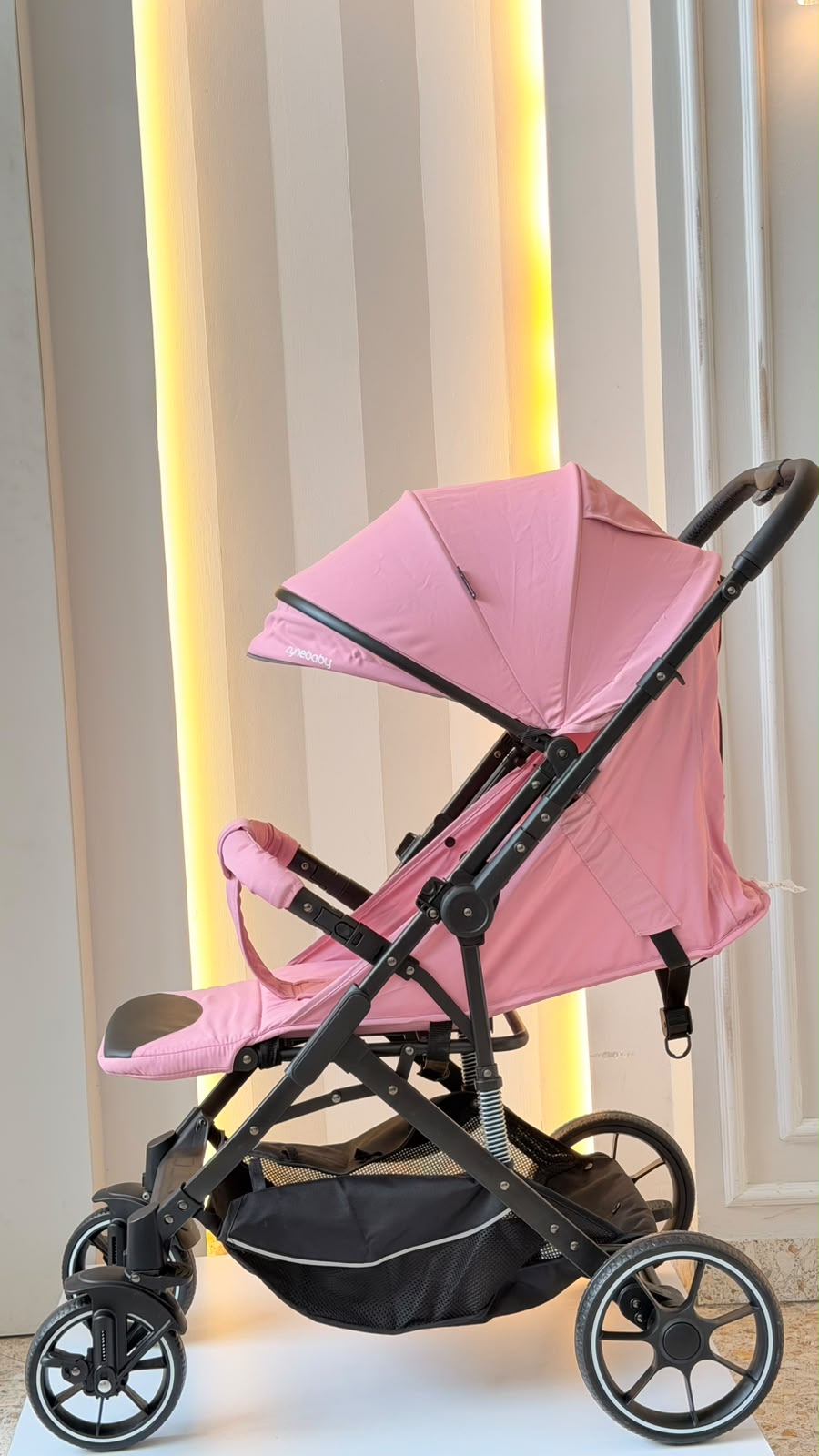 Coche para bebé rosa con asiento reclinable, arnés y barra frontal