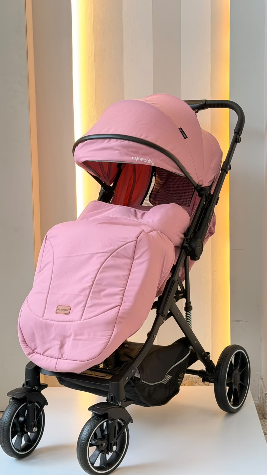 Asiento rosa reclinable y canasta inferior negra del coche para bebé