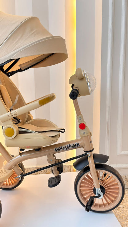 Detalle del triciclo Mickey beige con detalles dorados, pedales y rueda delantera