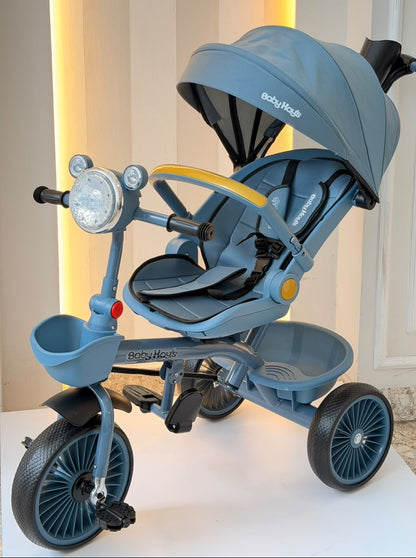 Triciclo infantil azul con manija trasera, capota y canastas laterales