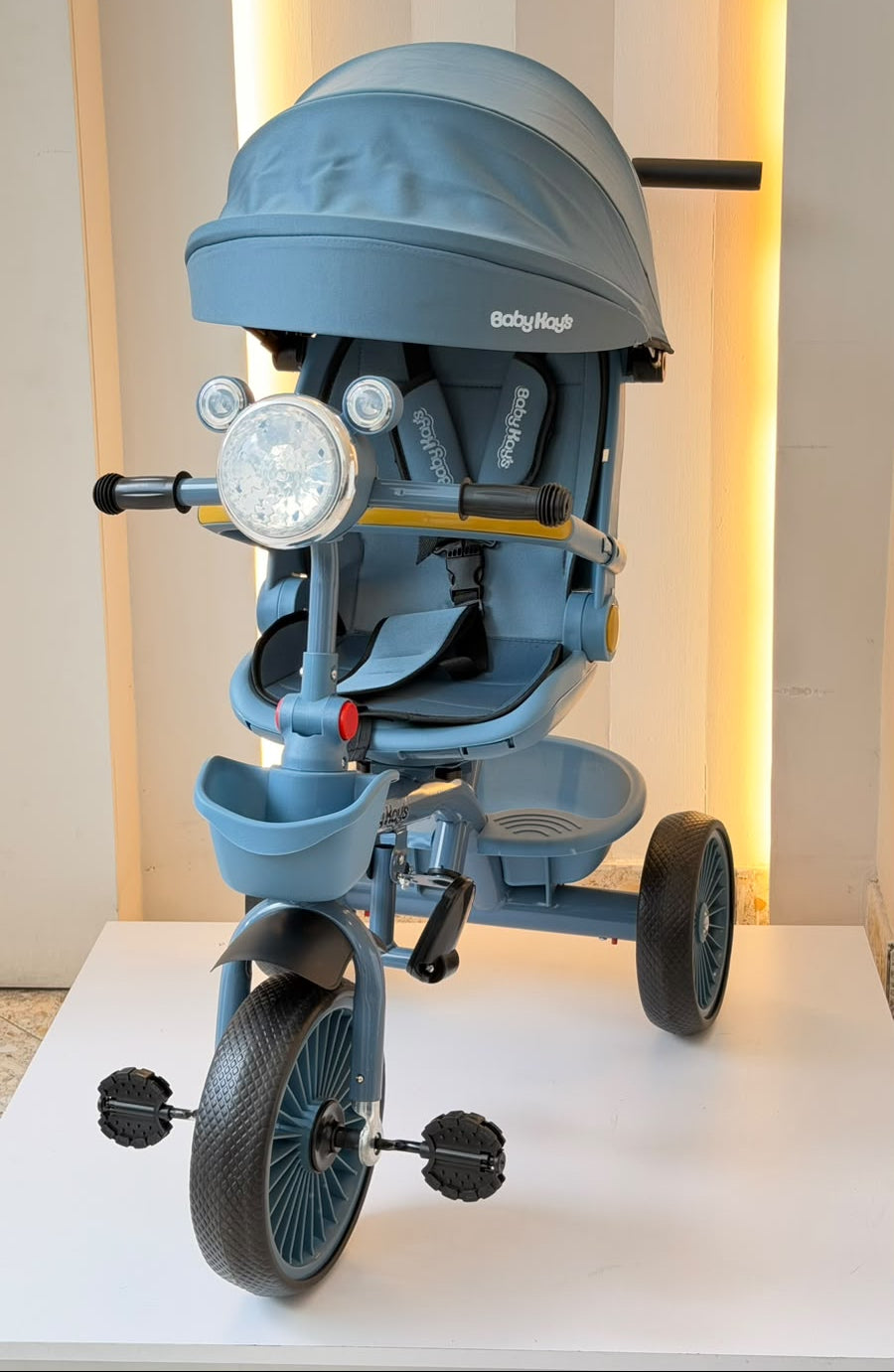 Detalle del triciclo infantil azul con asiento, arnés, reposapiés y canasta