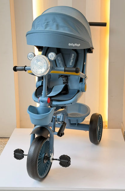 Detalle del triciclo infantil azul con asiento, arnés, reposapiés y canasta