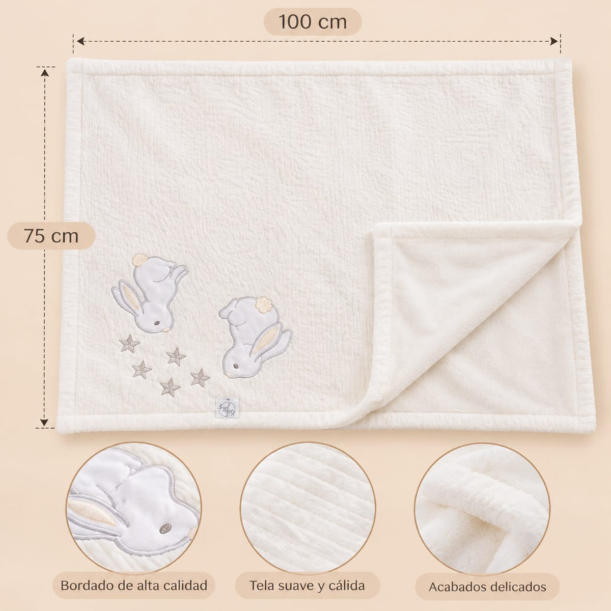 Manta blanca con conejitos bordados y medidas indicadas de 100 por 75 centímetros