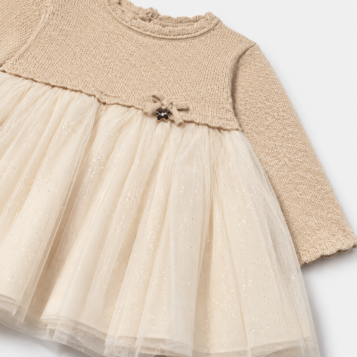 Detalle del lazo decorativo y la falda de tul con brillos del vestido combinado hojaldre para bebé niña